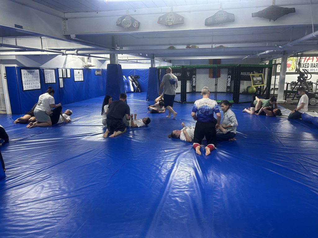 Women practice ground techniques in pairs on the blue mats during a women’s self-defense seminar at North Georgia Hayastan MMA Academy in Dalton, Georgia