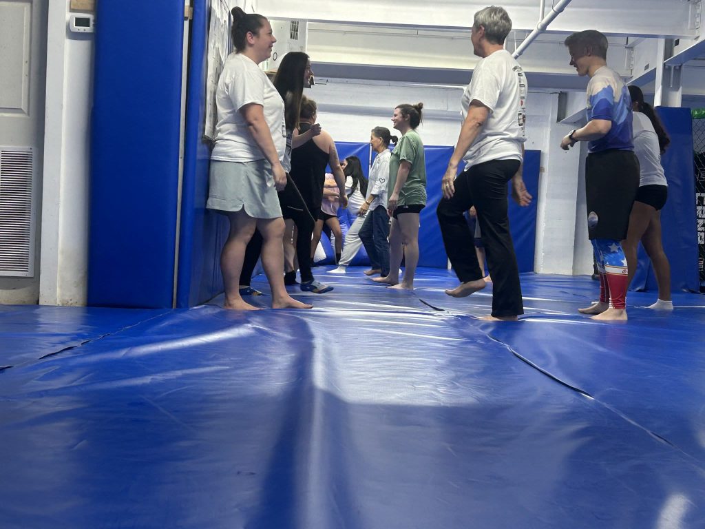 Women line up along the padded wall on the blue mats during a women’s self-defense seminar at North Georgia Hayastan MMA Academy in Dalton, Georgia