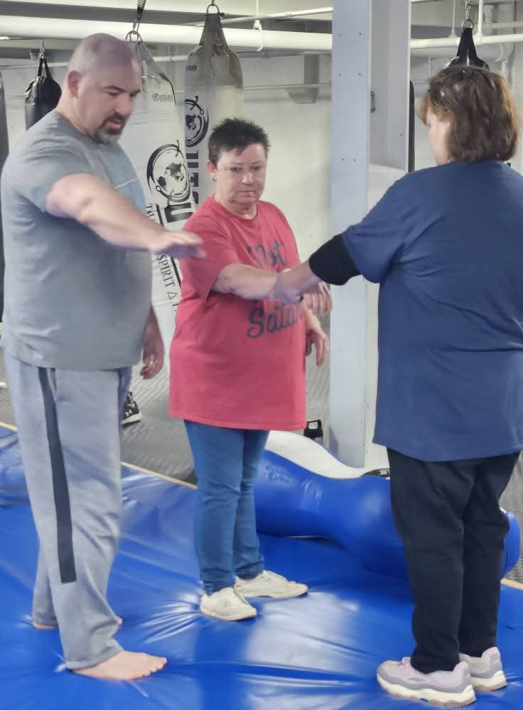 An assistant instructor teaching a wrist-grab escape to participants